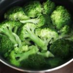 Bright green broccoli florets boiling in a pot for a fresh, healthy meal.