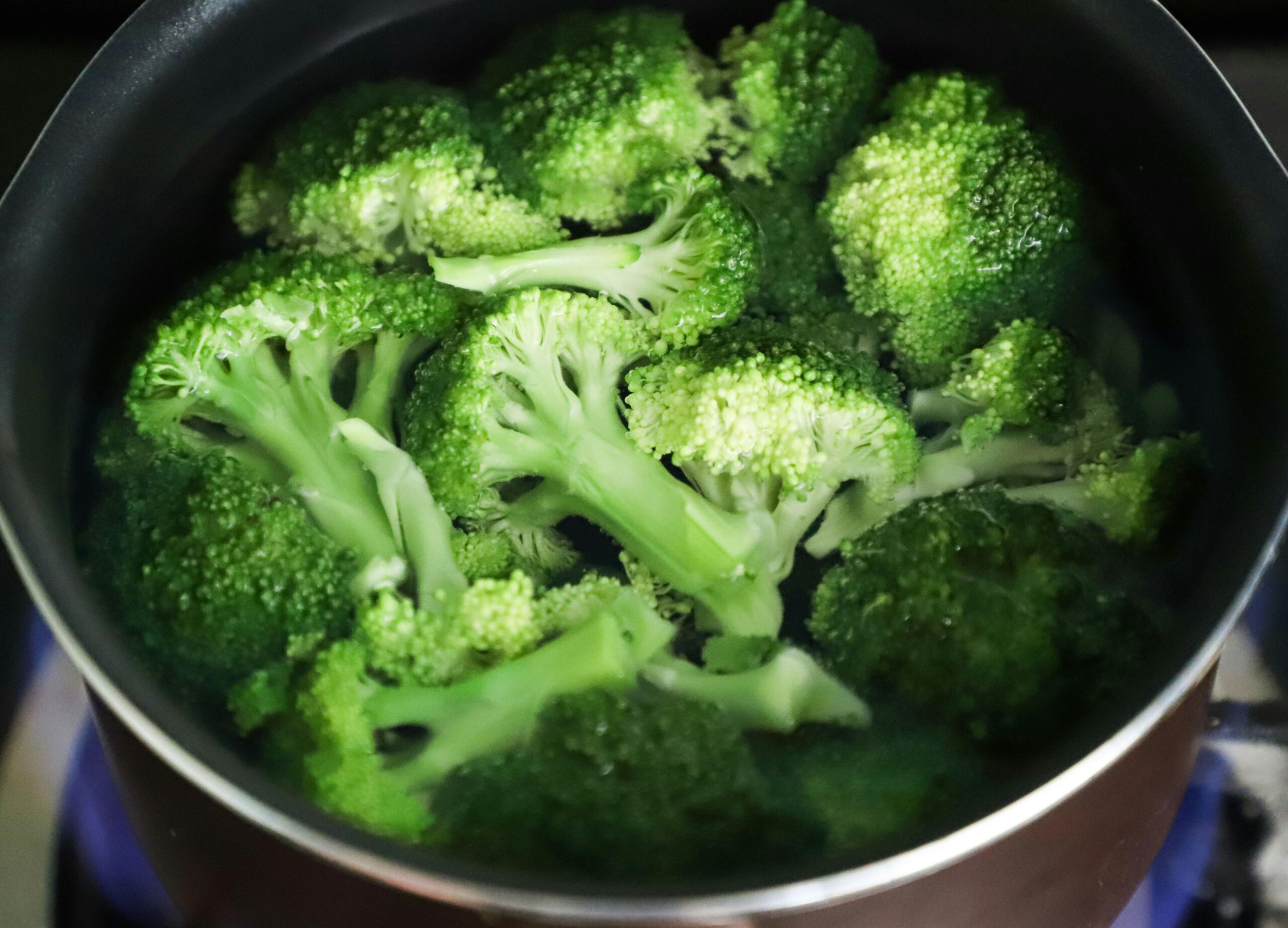 Bright green broccoli florets boiling in a pot for a fresh, healthy meal.