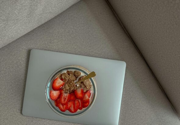 Delicious yogurt bowl with strawberries and granola on a laptop, perfect for breakfast or snack ideas.