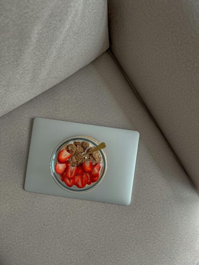 Delicious yogurt bowl with strawberries and granola on a laptop, perfect for breakfast or snack ideas.