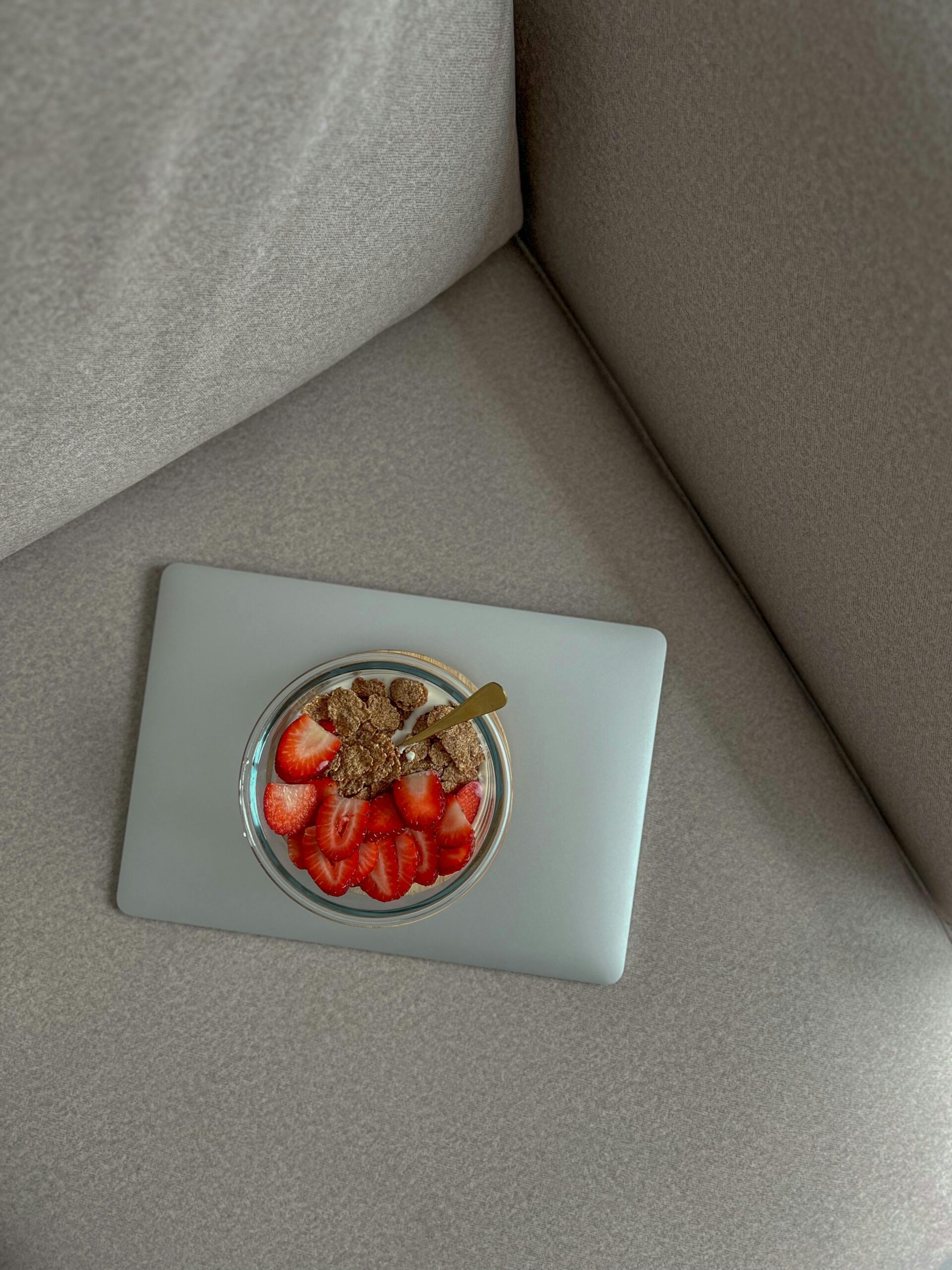 Delicious yogurt bowl with strawberries and granola on a laptop, perfect for breakfast or snack ideas.