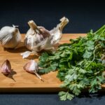Fresh garlic bulbs and parsley leaves arranged on a wooden cutting board, perfect for culinary and cooking stock images.