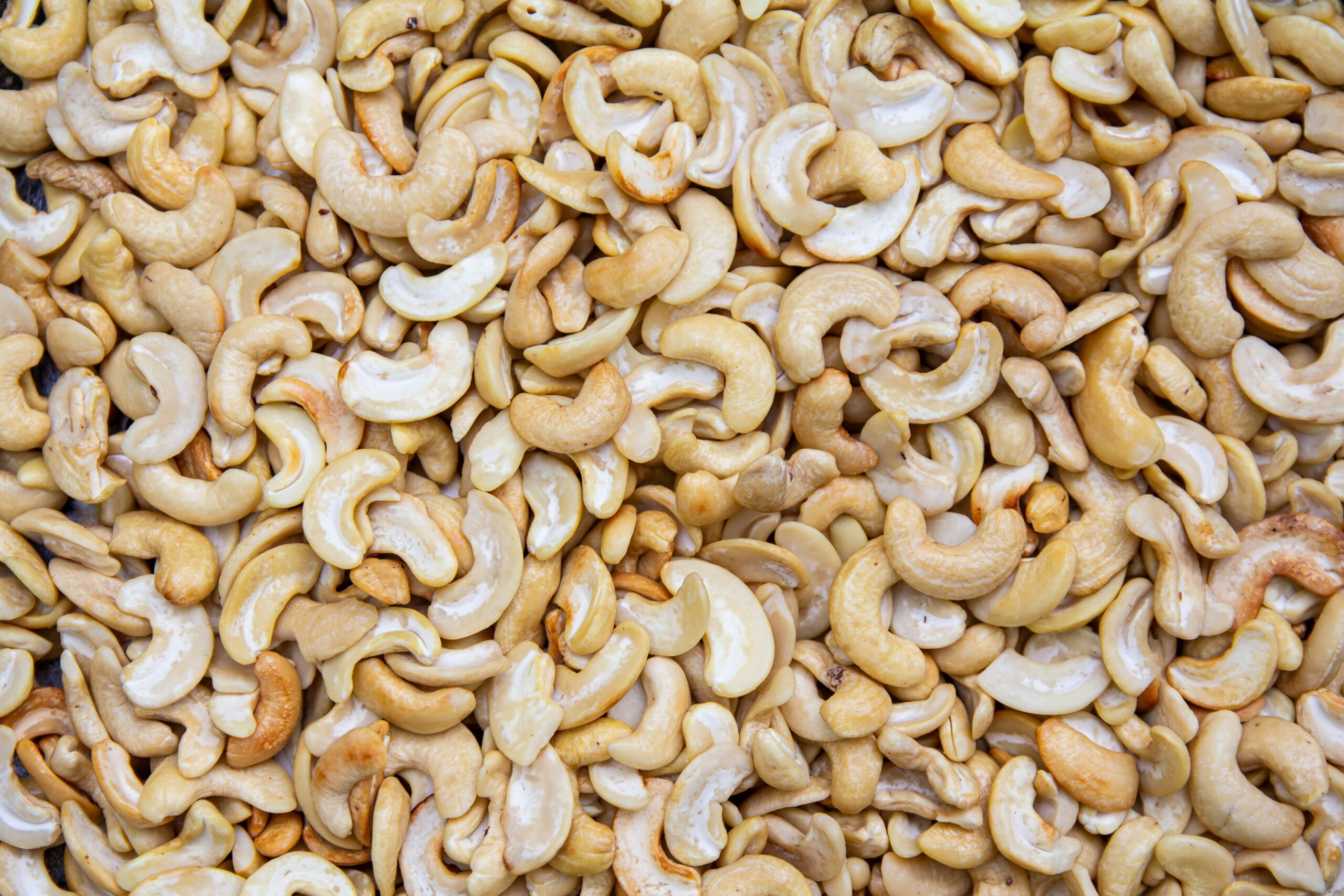A detailed close-up of roasted cashew nuts creating a textured, appetizing backdrop.